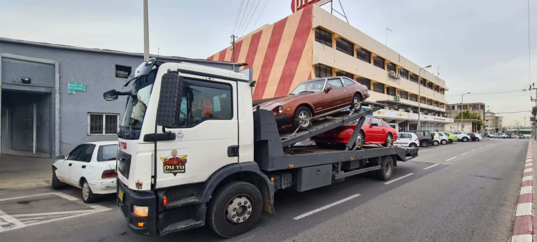 משאית גרר מובילה שני רכבים ברחוב